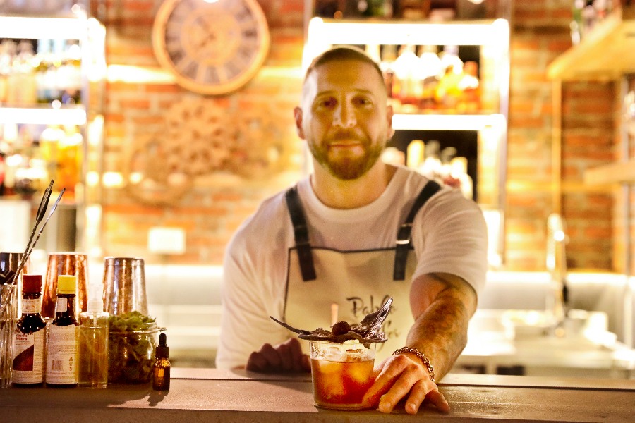 Fotogtrafía de uno de los bartenders del bar Enigma exhibiendo uno de los diversos tragos que ofrecen en este lugar.
