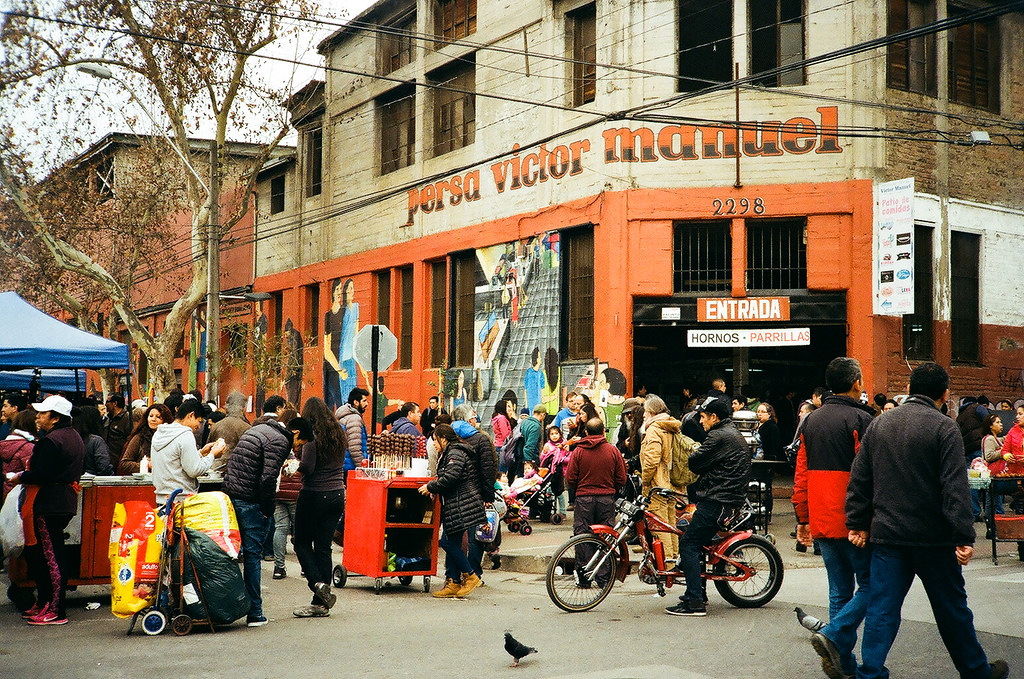 La imagen muestra una de las esquinas principales del Persa Bío Bío, donde se puede observar la gran cantidad de comercio y las personas que recorren el lugar.
