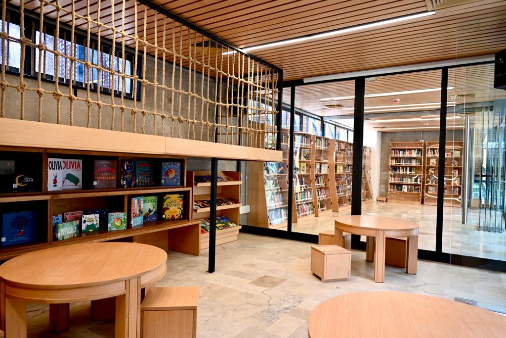 Imagen del interior de la cafetería literaria parque Bustamante, donde se aprecian algunas de las mesas, libros y al fondo repisas llenas de libros. 