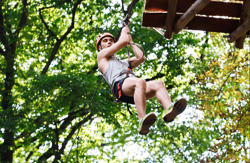 Persona colgado de un arnés practicando canopy al aire libre