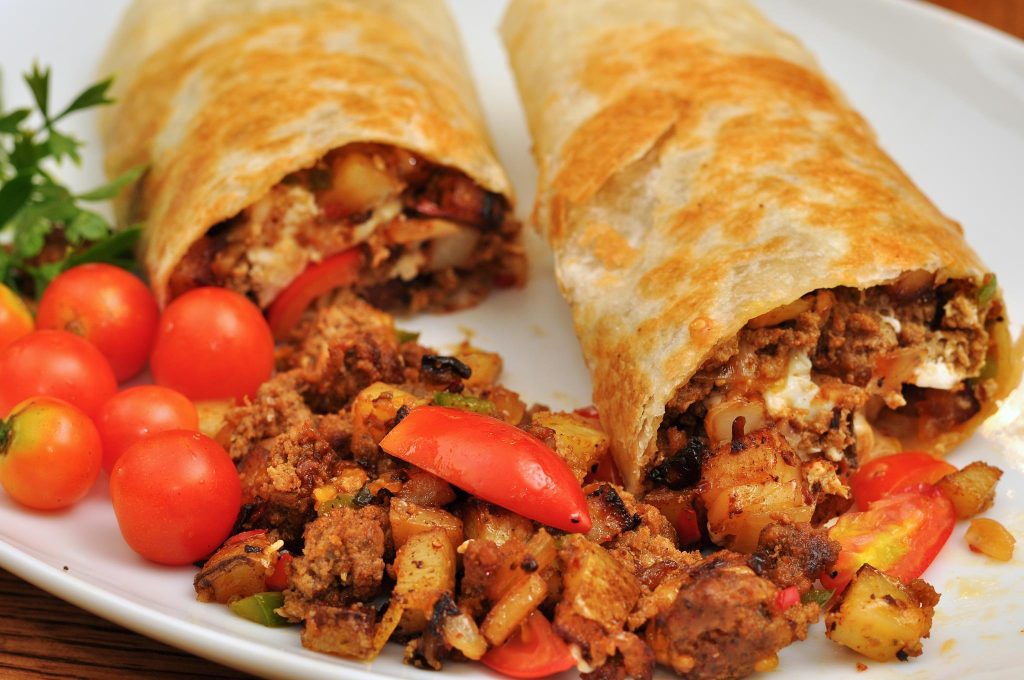 Burritos norteños sobre un plato junto a unos tomates cherry. Licencia Creative Commons