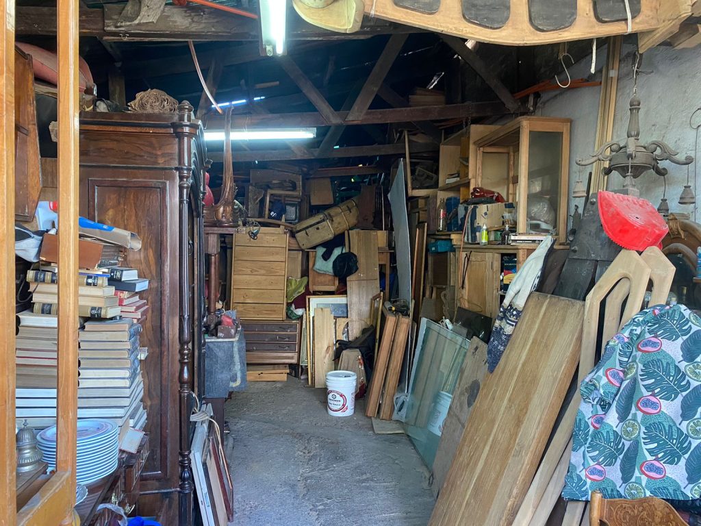 Foto del interior de Antiguedades "Miguel Núñez", en donde podemos ver diversos muebles y objetos desordenados.