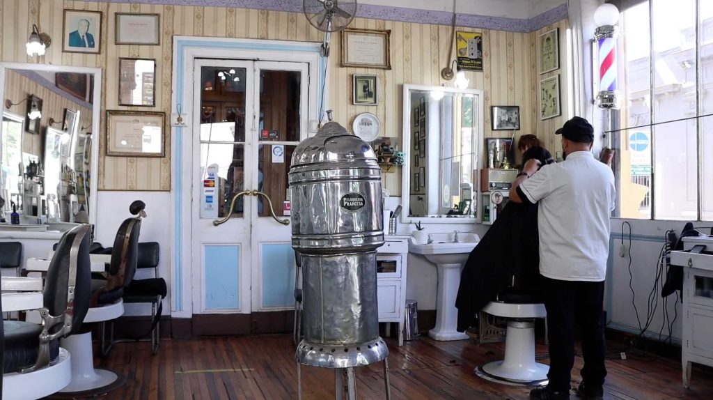 Fotografía del interior de la Peluquería Francesa, donde se muestra a nuestro entrevistado, Juan Ángel, cortando el pelo a un cliente (Fotografía de Indigo Prado).