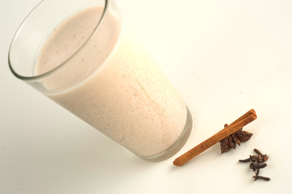 Vaso de horchata en una mesa junto a una rama de canela